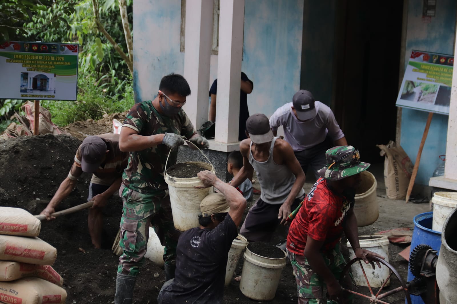 Di Dusun Kunir RT 01 RW 09, Desa Gumelem Kulon, Kecamatan Susukan, Minggu (26/7/2026), warga dan prajurit bahu-membahu melangsir material menuju mesin molen guna mempercepat pembangunan jalan rabat beton sepanjang 737 meter, lebar 2,5 meter, dan tebal 15 sentimeter.