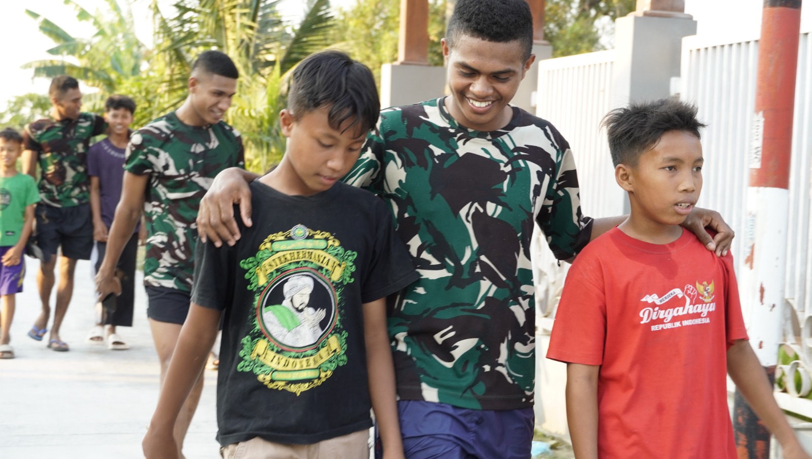 Kehangatan antara prajurit TNI dan masyarakat terlihat ketika sejumlah anggota Satgas berjalan berdampingan dengan anak-anak desa. Suasana santai dan penuh canda menjadi gambaran kedekatan yang terjalin selama pelaksanaan program TMMD.