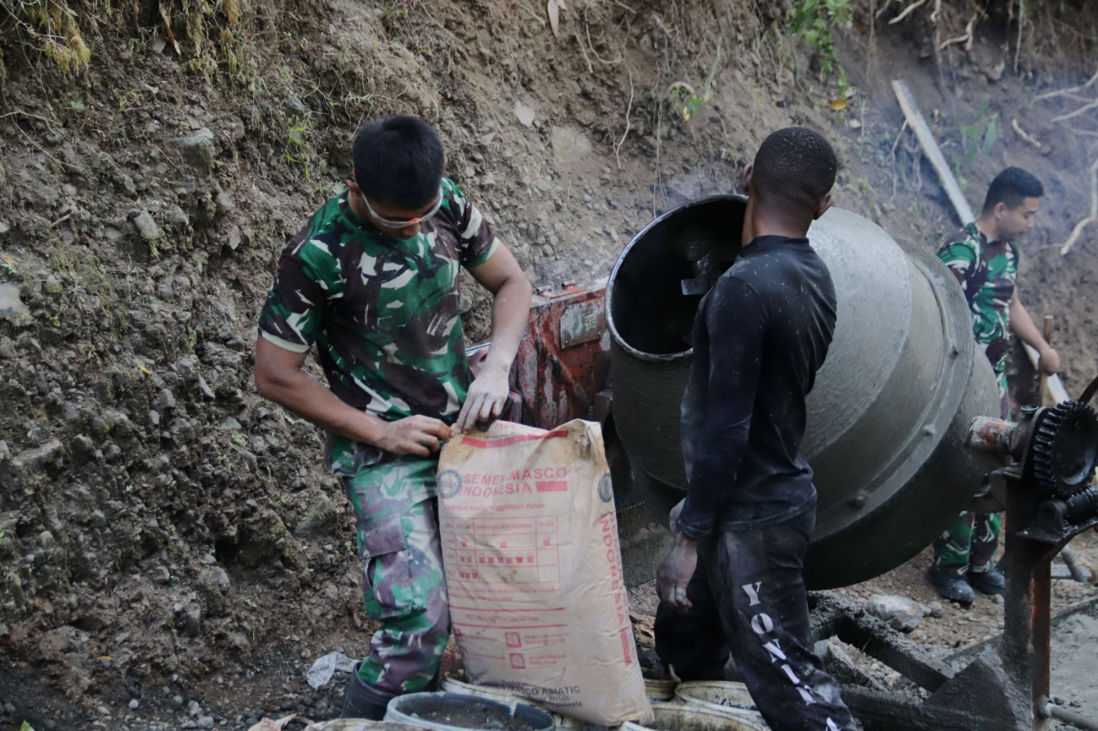 Bertempat di Dusun Kunir, Desa Gumelem Kulon, Kecamatan Susukan, Minggu (19/7/2026), Pratu Figo terlihat teliti meratakan adukan beton bersama warga.