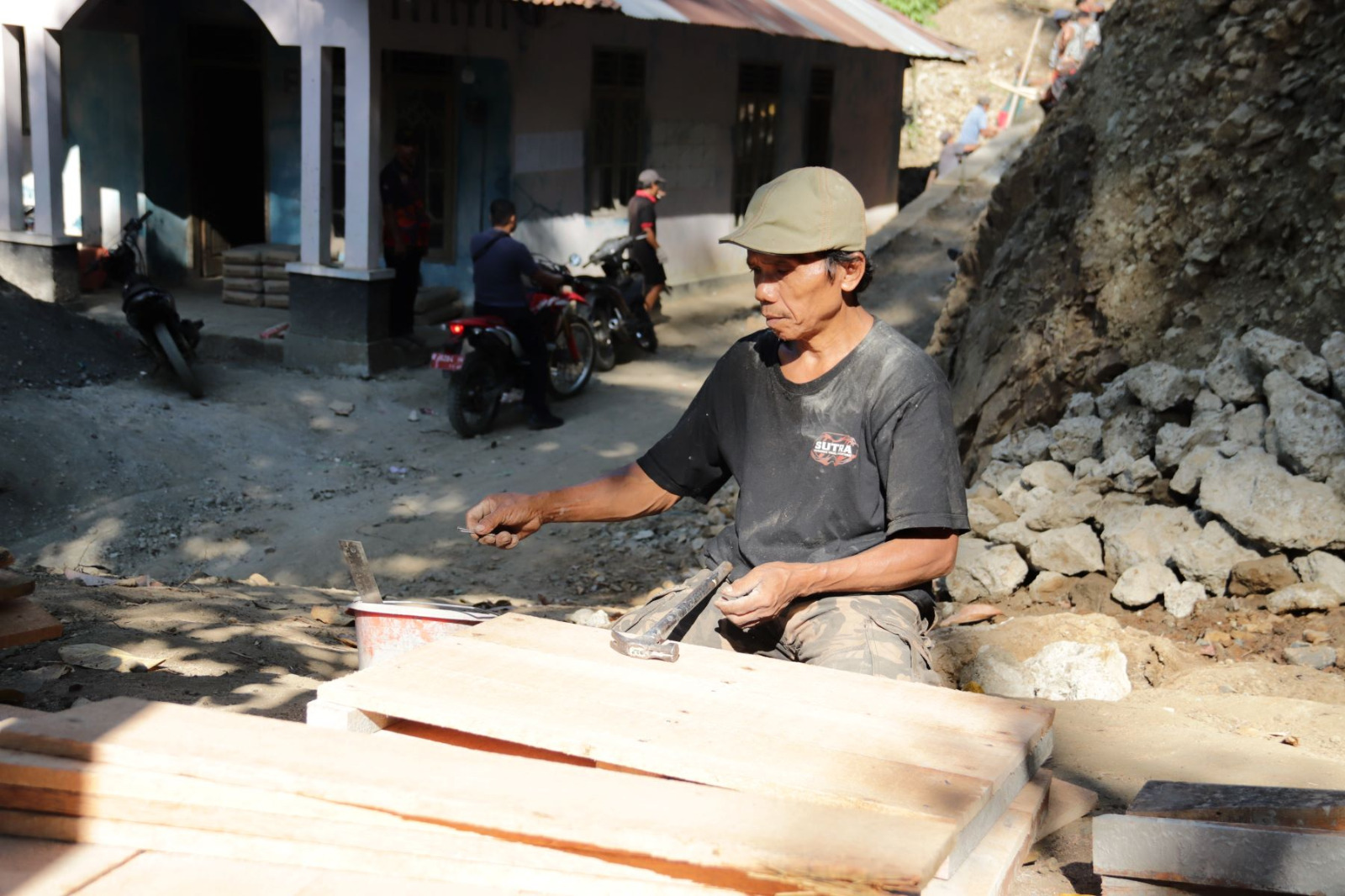 Salah satu wujud nyata partisipasi warga terlihat dari keterlibatan Madrohim (59), warga Dusun Kunir RT 01/RW 09, Desa Gumelem Kulon, Kecamatan Susukan, yang turut merakit papan bekisting untuk pembangunan plat beton, Selasa (21/07/2026).
