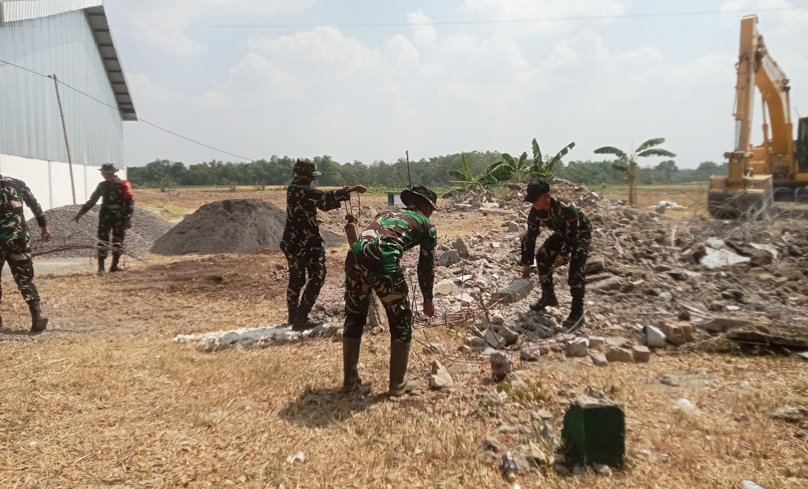 Personel Satgas TMMD bersama warga turun langsung membersihkan puing-puing bangunan lama sebagai tahap awal pembangunan kawasan pujasera (rest area), Sabtu (18/7/2026).