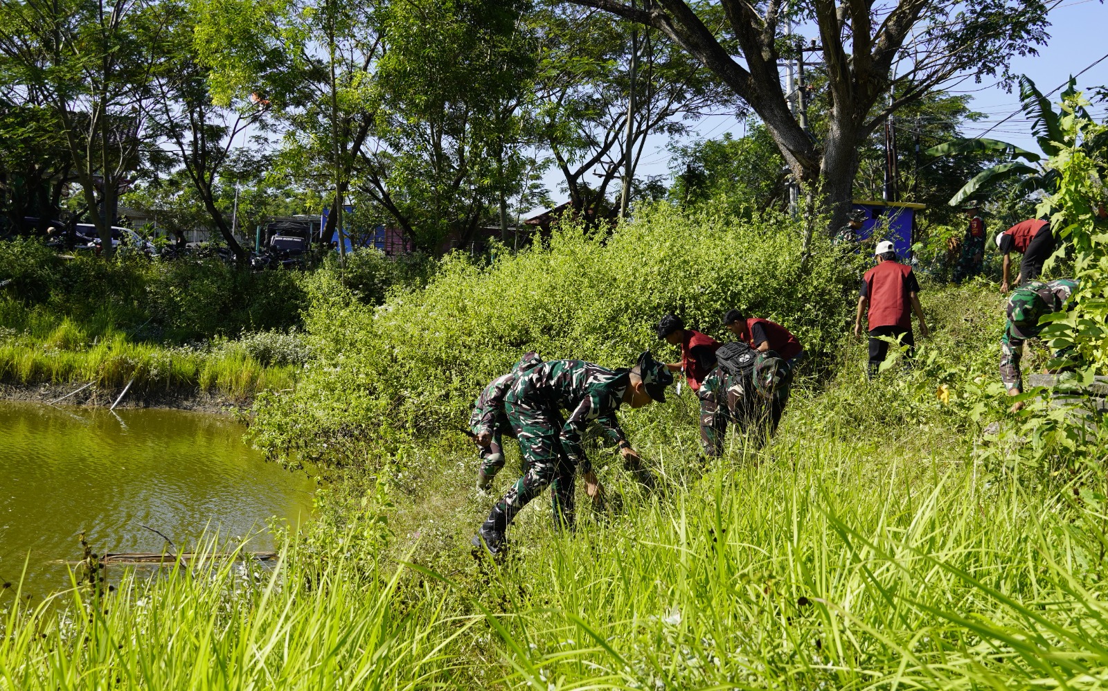 Selain mengerjakan pembangunan fisik, personel Satgas TMMD bersama mahasiswa Kuliah Kerja Nyata Tematik Kolaboratif (KKNTK) Universitas Bojonegoro (Unigoro) menggelar aksi bersih-bersih di kawasan Embung Bekatul, Kamis (16/7/2026).