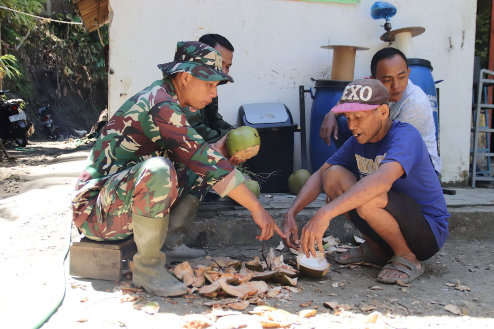 Serda Eko bersama salah seorang warga, Kabul, memanfaatkan momen untuk menikmati segarnya air kelapa muda sebelum kembali melanjutkan pekerjaan, Senin (27/7/2026).