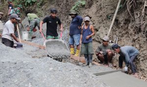 Salah satunya diperlihatkan Pratu Iwan yang tanpa henti mendorong angkong berisi adukan beton menuju titik pengecoran jalan, Jumat (31/7/2026).