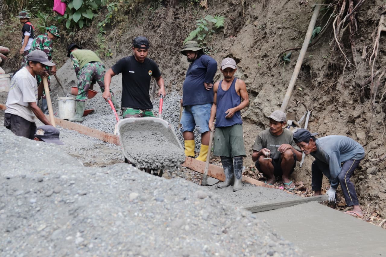 Salah satunya diperlihatkan Pratu Iwan yang tanpa henti mendorong angkong berisi adukan beton menuju titik pengecoran jalan, Jumat (31/7/2026).