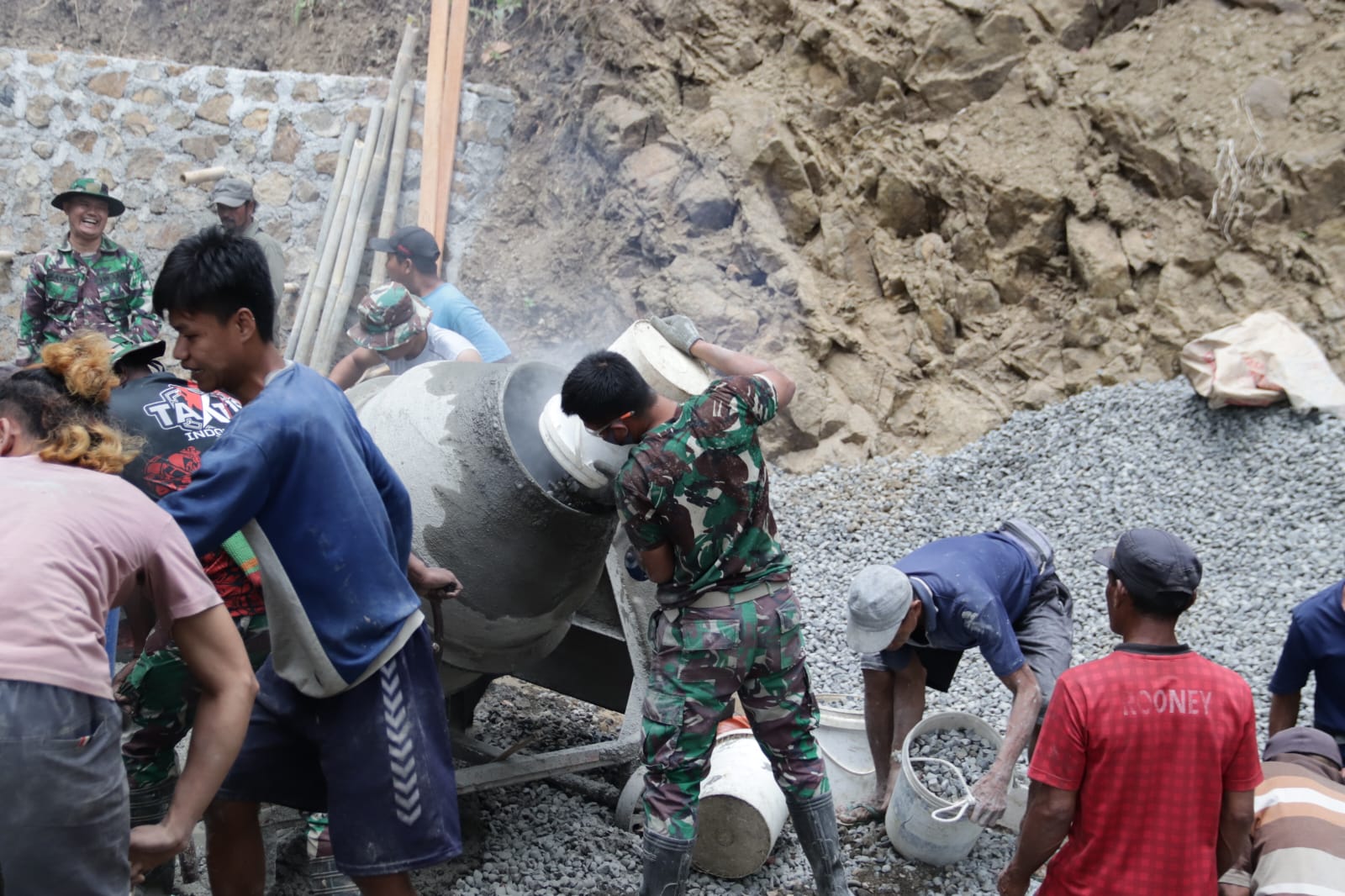 Salah satunya ditunjukkan Pratu Farhan dari Yonif 405/Suryakusuma yang bersama warga tanpa henti memastikan pasokan material untuk pengecoran jalan rabat beton di Dusun Kunir RT 01/RW 09, Desa Gumelem Kulon, Kecamatan Susukan, Selasa (28/7/2026).