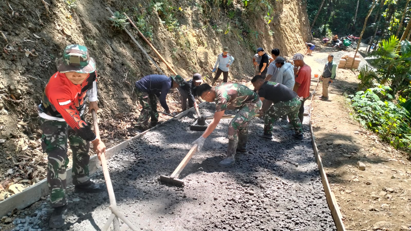 Sebuah talang seng menjadi andalan untuk menyalurkan adukan beton dari mesin molen menuju titik pengecoran di Dusun Kunir RT 01/09, Desa Gumelem Kulon, Kecamatan Susukan, Senin (27/7/2026).