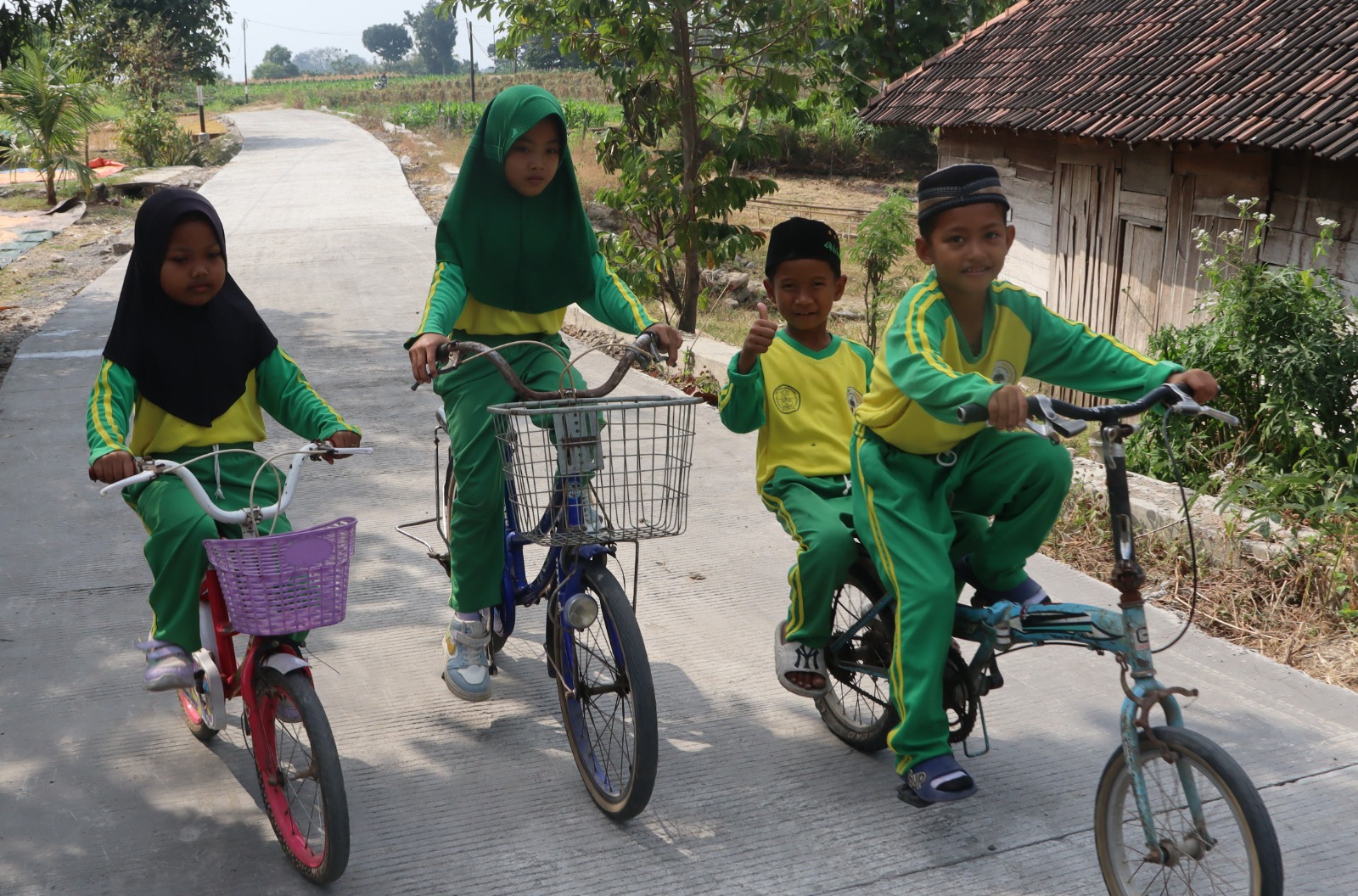 Dengan sepeda yang mereka kayuh penuh semangat, perjalanan menuju sekolah kini terasa lebih nyaman setelah akses jalan di wilayah mereka berubah menjadi lebih baik.