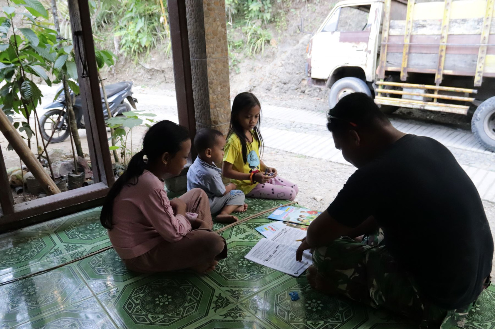 Di sela waktu istirahat, Pratu Brian Sitorus memanfaatkan kesempatan untuk mendampingi anak-anak belajar di Dusun Kunir RT 01 RW 09, Desa Gumelem Kulon, Kecamatan Susukan, Rabu (22/7/2026).