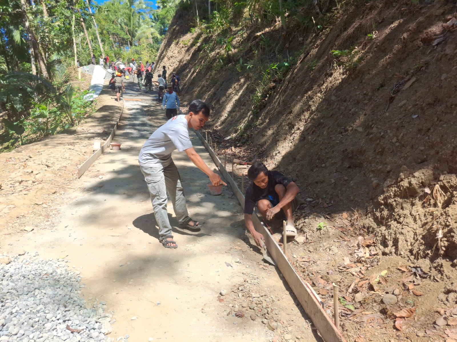 Salah satunya ditunjukkan Pratu Farhan dari Yonif 405/Suryakusuma yang bersama warga tanpa henti memastikan pasokan material untuk pengecoran jalan rabat beton di Dusun Kunir RT 01/RW 09, Desa Gumelem Kulon, Kecamatan Susukan, Selasa (28/7/2026).