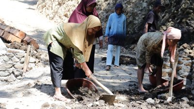 Dengan penuh semangat, ia mendorong angkong berisi tanah untuk mendukung pekerjaan pengecoran rabat beton sepanjang 737 meter, lebar 2,5 meter, dan tebal 0,15 meter di Dusun Kunir RT 01/09, Desa Gumelem Kulon, Kecamatan Susukan, Senin (27/07/2026).