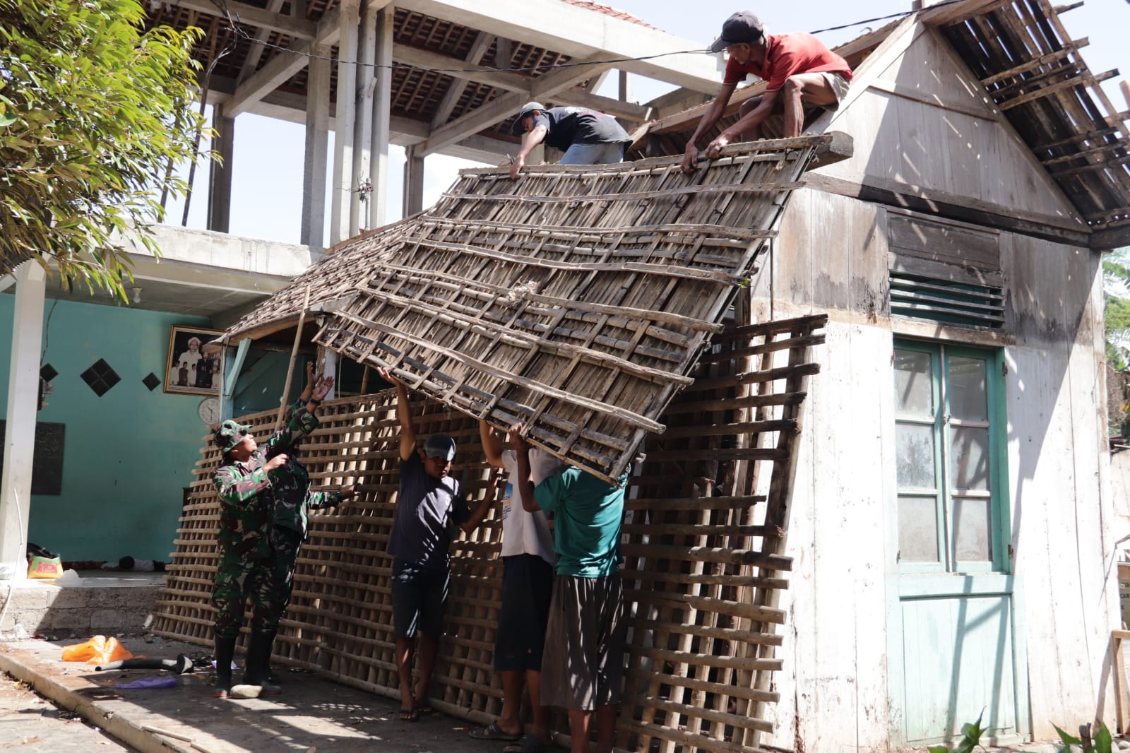 Di bawah komando Danramil 09/Susukan Kapten Inf Masrukin, anggota Satgas TMMD Reguler ke-129 TA 2026 Kodim 0704/Banjarnegara bersama warga bergotong royong menurunkan atap rumah yang akan direhabilitasi melalui program Rumah Tidak Layak Huni (RTLH), Jumat (24/07/2026).