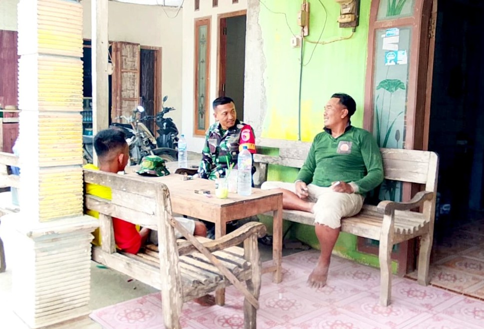 Serka Lasmidi, Babinsa Desa Kesongo, berbincang bersama warga di teras rumah dalam suasana penuh keakraban di sela pelaksanaan TMMD ke-129 Kodim 0813/Bojonegoro, Desa Kesongo, Kecamatan Kedungadem, Kamis (6/8/2026). Foto: Deni Ari Pandi/Sumber TMMD Bojonegoro.