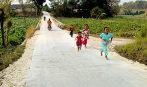 Anggi bersama teman-temannya bermain dan berlari di jalan cor hasil pembangunan TMMD ke-129 Kodim 0813 Bojonegoro di Dusun Mundu, Desa Kesongo, Kecamatan Kedungadem, Kabupaten Bojonegoro, Minggu (09/08/2026). Foto: Deni Ari Pandi/Sumber: TMMD Bojonegoro.
