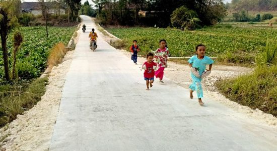 Anggi bersama teman-temannya bermain dan berlari di jalan cor hasil pembangunan TMMD ke-129 Kodim 0813 Bojonegoro di Dusun Mundu, Desa Kesongo, Kecamatan Kedungadem, Kabupaten Bojonegoro, Minggu (09/08/2026). Foto: Deni Ari Pandi/Sumber: TMMD Bojonegoro.