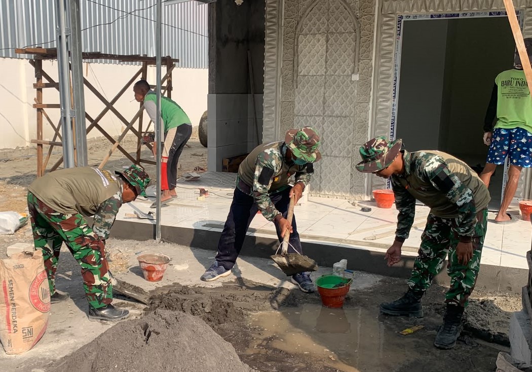 Mushola Masuk Tahap Akhir: Anggota Satgas TMMD ke-129 Kodim 0813 Bojonegoro bersama warga mengerjakan pemasangan keramik teras dan pengecatan mushola di kawasan rest area Desa Kesongo, Kecamatan Kedungadem, Jumat (7/8/2026).