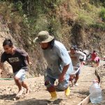 Gotong Royong di Tanjakan: Dua warga Desa Gumelem Kulon bekerja sama menarik dan mendorong angkong berisi adukan beton menuju lokasi pengecoran rabat beton dalam pelaksanaan TMMD Reguler ke-129 Kodim 0704/Banjarnegara, Jumat (7/8/2026).
