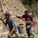 Foto: Praka Ari bersama Tono, warga Desa Gumelem Kulon, memikul adukan beton menggunakan bambu menuju lokasi pengecoran rabat beton pada pelaksanaan TMMD Reguler ke-129 Kodim 0704/Banjarnegara di Dusun Kunir RT 01/09, Kecamatan Susukan, Kamis (6/8/2026). Kebersamaan TNI dan warga menjadi kekuatan utama dalam mempercepat pembangunan infrastruktur desa. Foto: Deni Aripandi/Pendim Banjarnegara.
