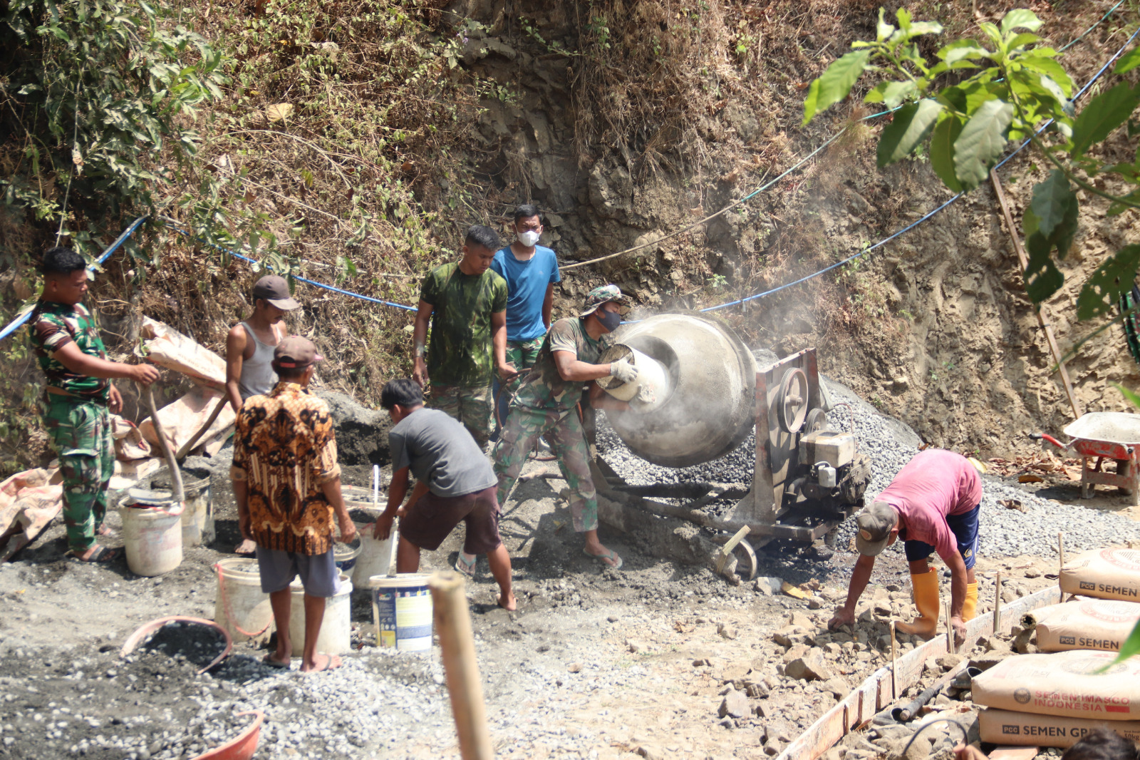 Kompak Mengisi Molen: Warga bersama anggota Satgas TMMD Reguler ke-129 Kodim 0704/Banjarnegara bergotong royong memasukkan material ke dalam mesin molen untuk mendukung pengecoran rabat beton sepanjang 737 meter di Dusun Kunir, Desa Gumelem Kulon, Kecamatan Susukan, Jumat (7/8/2026).