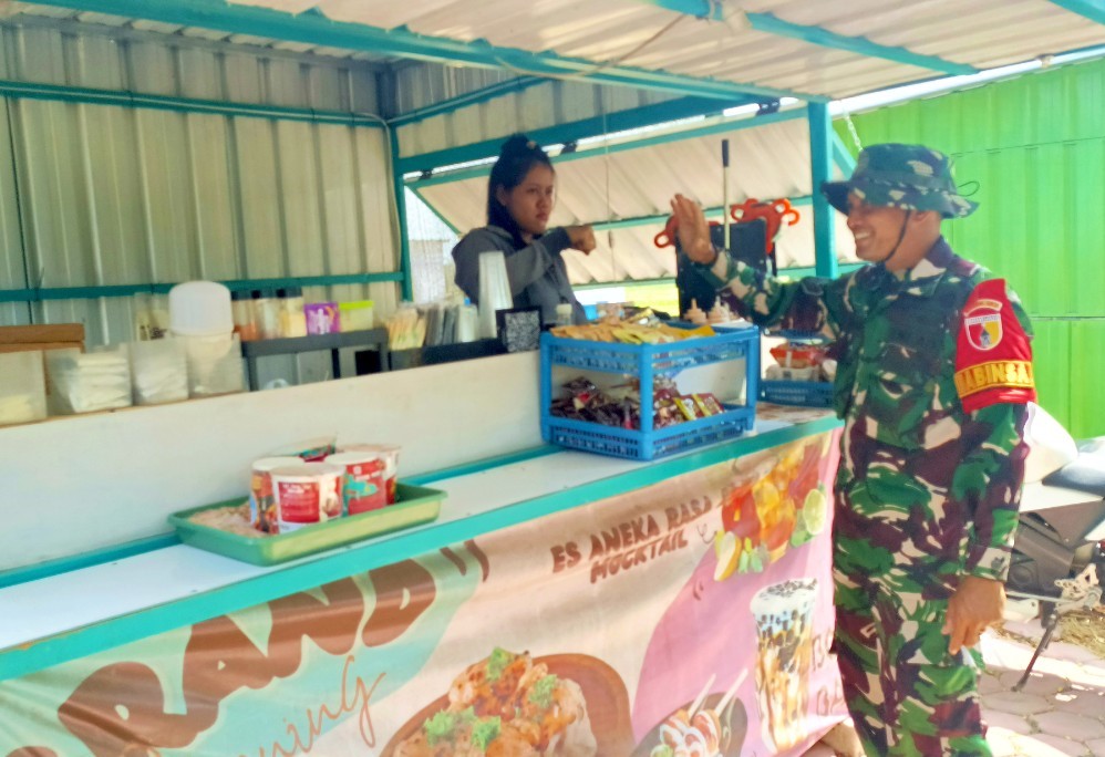 Babinsa Desa Kesongo Serka Lasmidi mendampingi pelaku UMKM saat menempati booth container di kawasan Rest Area Terpadu Desa Kesongo, Kecamatan Kedungadem, Kabupaten Bojonegoro, Selasa (11/8/2026). Foto: Deni Flamboyan/Sumber TMMD Bojonegoro