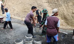 Personel TNI dan Polri bahu-membahu bersama warga melangsir batu split untuk mendukung pembangunan rabat beton di Dusun Kunir RT 01/RW 09, Desa Gumelem Kulon, Kecamatan Susukan, Minggu (2/8/2026).