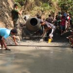Anggota Satgas TMMD bersama warga Desa Gumelem Kulon bahu-membahu mengerjakan pengecoran rabat beton sebagai bagian dari pembangunan infrastruktur desa, Sabtu (09/08/2026).