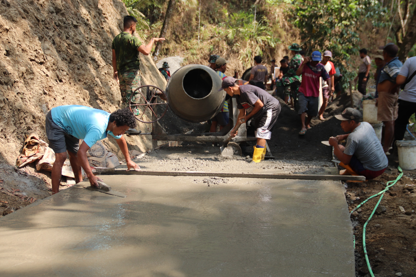 Anggota Satgas TMMD bersama warga Desa Gumelem Kulon bahu-membahu mengerjakan pengecoran rabat beton sebagai bagian dari pembangunan infrastruktur desa, Sabtu (09/08/2026).