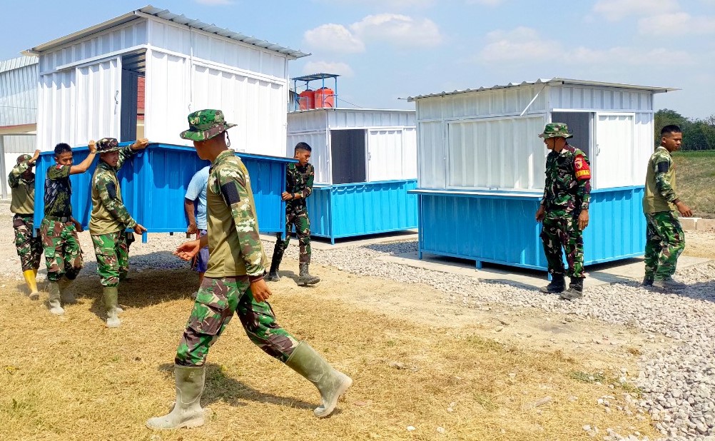 Personel Satgas TMMD ke-129 Kodim 0813/Bojonegoro bersama masyarakat saat memindahkan dan menempatkan enam unit booth container UMKM di Rest Area Terpadu Desa Kesongo, Kecamatan Kedungadem, Kabupaten Bojonegoro, Senin (10/8/2026). Foto: Deni Flamboyan/Sumber TMMD Bojonegoro