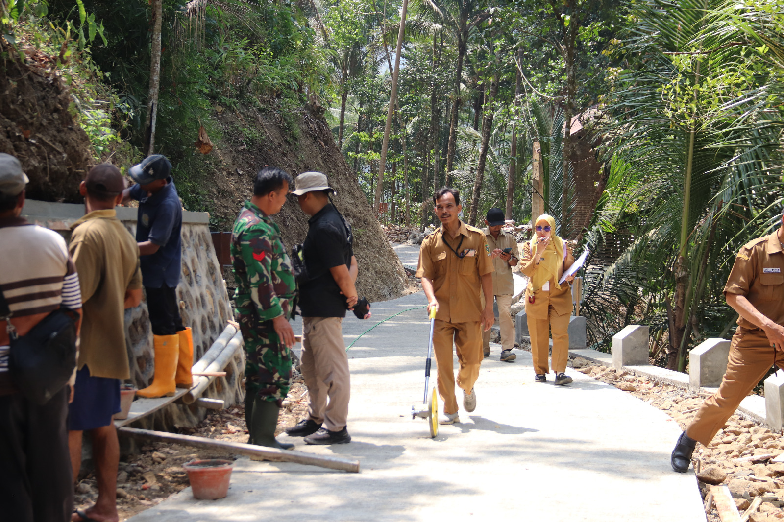 Cek Kualitas Pembangunan: Sekdes Gumelem Kulon Katim mendampingi Tim Dispermades PPKB Kabupaten Banjarnegara saat melakukan pengukuran rabat beton hasil pembangunan TMMD Reguler ke-129 Kodim 0704/Banjarnegara di Dusun Kunir, Desa Gumelem Kulon, Jumat (7/8/2026).