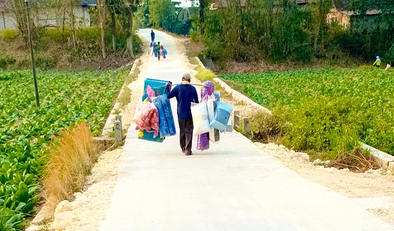 Pedagang keliling melintas di jalan beton hasil pembangunan program TMMD ke-129 di Dusun Mundu, Desa Kesongo, Kecamatan Kedungadem, Kabupaten Bojonegoro, Senin (10/8/2026). Foto: Deni Flamboyan/Sumber TMMD Bojonegoro
