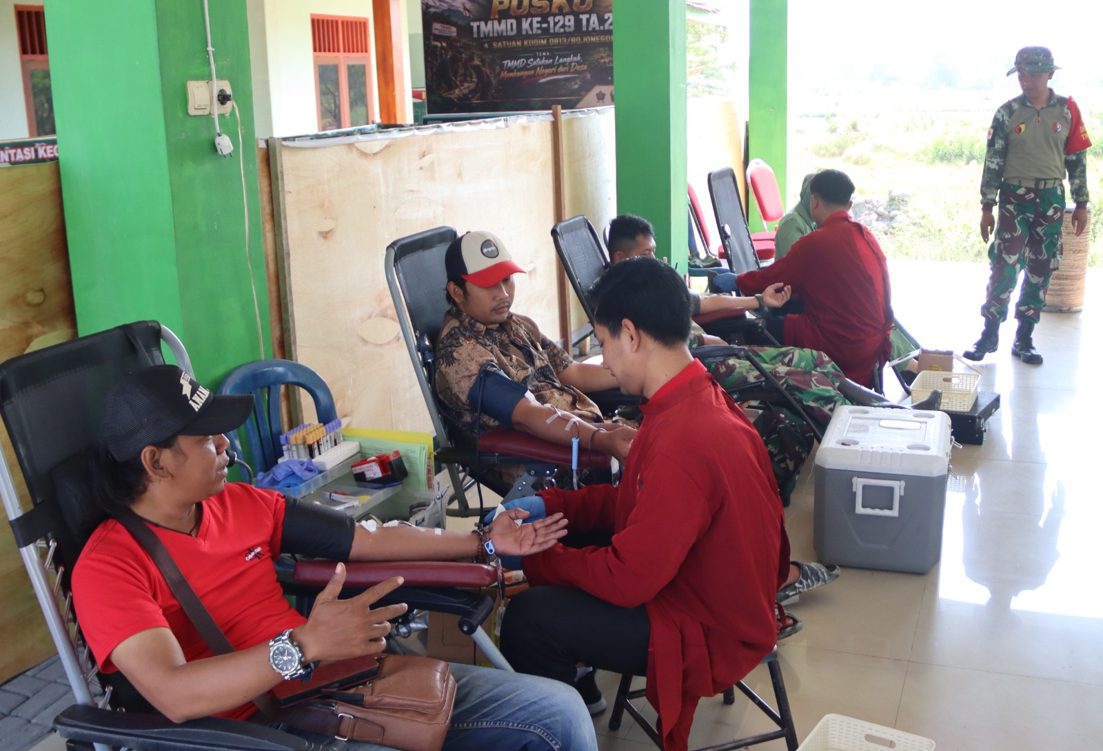 Personel Satgas TMMD ke-129 Kodim 0813 Bojonegoro bersama masyarakat mengikuti kegiatan donor darah dan sosialisasi kesehatan di Balai Desa Kesongo, Kecamatan Kedungadem, Bojonegoro.