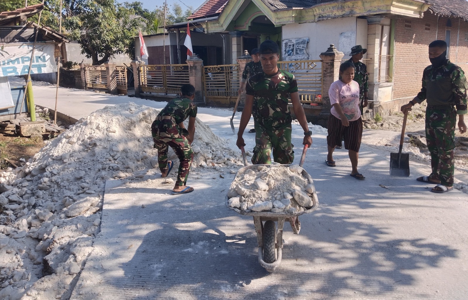 Satgas TMMD ke-129 Kodim 0813/Bojonegoro bersama warga mengangkut dan meratakan material pedel untuk memperkuat bahu jalan cor di Dusun Mundu, Desa Kesongo, Kecamatan Kedungadem, Kabupaten Bojonegoro.