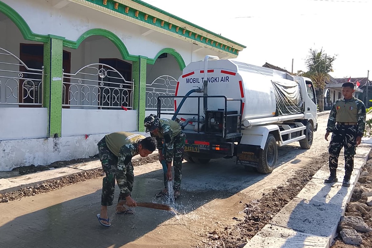 Anggota Satgas TMMD ke-129 Kodim 0813 Bojonegoro melakukan penyiraman atau curing jalan cor di Dusun Krebet, Desa Kesongo, Kecamatan Kedungadem, Kabupaten Bojonegoro, Minggu (09/08/2026). Foto: Deni Ari Pandi/Sumber: TMMD Bojonegoro.