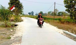 Warga melintas di jalan cor beton hasil pembangunan TMMD ke-129 sepanjang 550 meter di Dusun Kedungpandan, Desa Kesongo, Kecamatan Kedungadem, Kabupaten Bojonegoro, Senin (10/8/2026). Foto: Deni Flamboyan/Sumber TMMD Bojonegoro