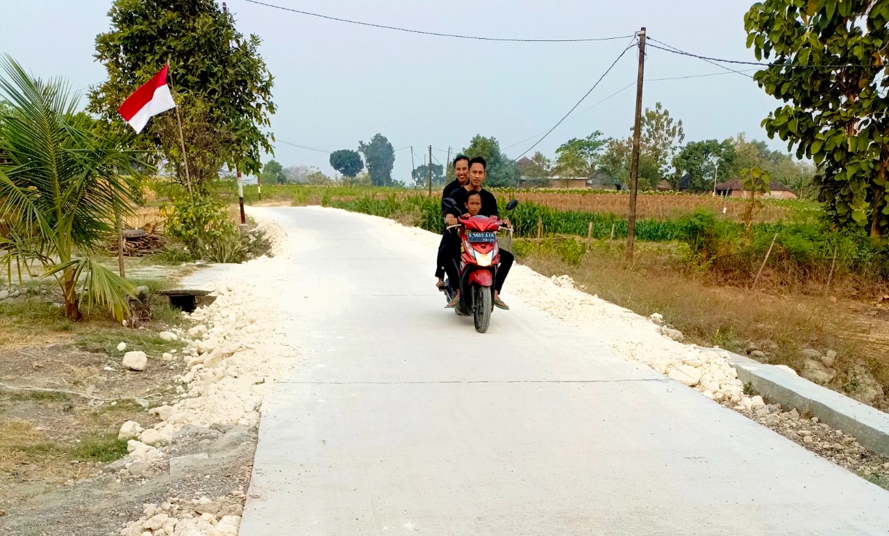Warga melintas di jalan cor beton hasil pembangunan TMMD ke-129 sepanjang 550 meter di Dusun Kedungpandan, Desa Kesongo, Kecamatan Kedungadem, Kabupaten Bojonegoro, Senin (10/8/2026). Foto: Deni Flamboyan/Sumber TMMD Bojonegoro